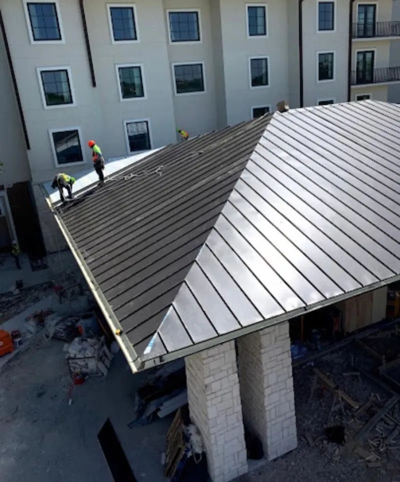 Crew installing standing seam metal roof panels on a commercial project in Hazelwood